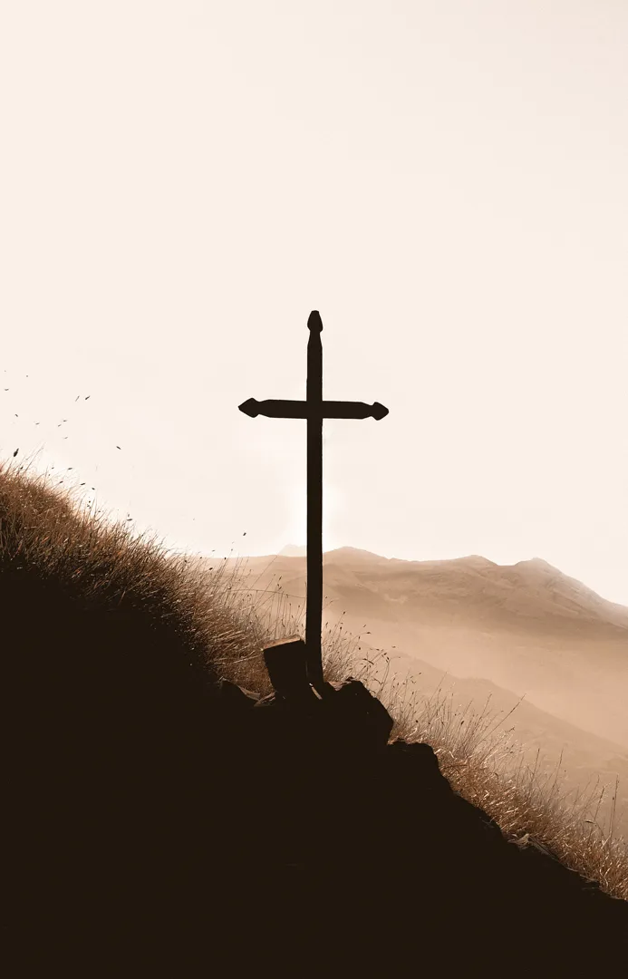 Silhouetted cross on a hillside at dawn